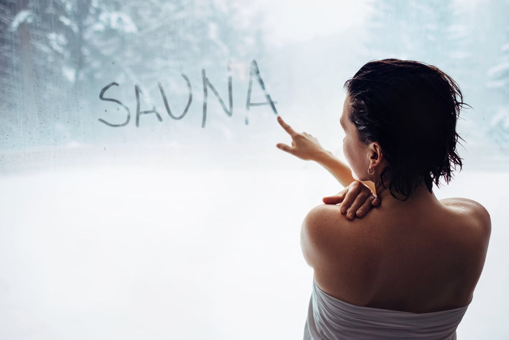 Woman wrote "sauna" word on misted window